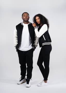 A men's and women's wool blend varsity jacket in black and cream, featuring contrasting sleeves and a logo.