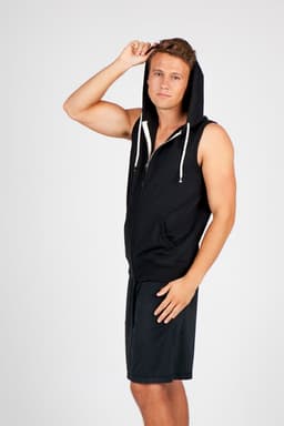 A sleeveless black hoodie with a zip and hood, worn by a model posing in shorts. The hoodie has a logo.