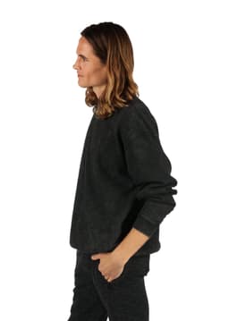 Unisex stone wash sweatshirt in a dark shade, featuring a relaxed fit and long sleeves. Model displayed in profile.