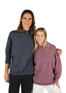 Two people wearing unisex stone wash sweatshirts in navy blue and a muted purple, with one sweatshirt featuring a logo.