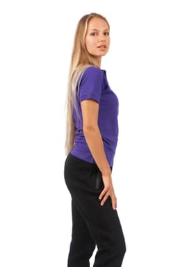 A woman stands sideways wearing a purple 100% cotton pique knit polo shirt and black pants. The shirt features a logo.