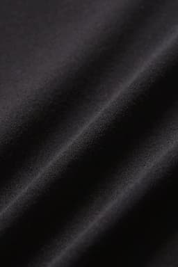 A close-up of black fabric displaying a smooth texture and gentle folds, suitable for leggings.