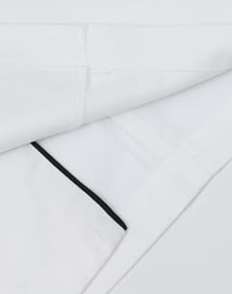 A unisex executive chef jacket in white with black detailing and a logo on the fabric.
