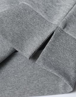 A grey unisex crew neck sweater featuring ribbed cuffs and hem with a logo present.