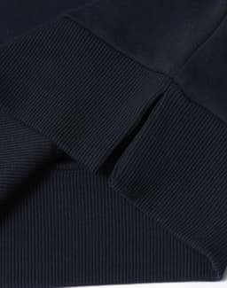 A dark navy crew neck sweater featuring ribbed cuffs and hem, displaying a logo on the fabric.