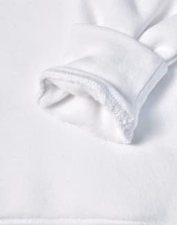 A close-up of a white fleecy hoodie sleeve featuring a soft, textured cuff. It has a logo on the fabric.