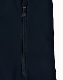 A dark navy softshell jacket featuring a zippered pocket and a sleek design. The jacket also has a logo.