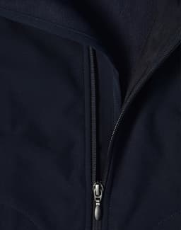 A close-up of a navy softshell vest featuring a zippered front and a fleece lining. The vest has a logo on it.