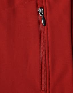 A close-up of a red softshell vest featuring a zippered pocket and a logo.