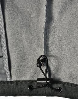 A grey softshell full zip hoodie featuring a drawstring toggle and fleece interior. It has a logo on the fabric.