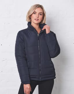 A navy heavy quilted puffer jacket with a zip and high collar, featuring a woman posing against a white brick wall.