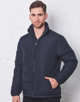 A navy heavy quilted puffer jacket with a zippered front and high collar, modelled by a man against a white wall.