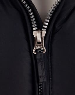 A heavy quilted black jacket with a silver zip featuring the brand logo, showcasing a close-up of the zipper area.
