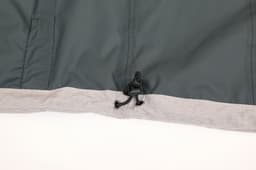 A grey and dark green waterproof performance jacket, featuring a hook detail at the hem. It has a logo.