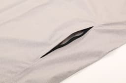 A light grey performance jacket featuring a zipped pocket on the side, designed for waterproof protection.