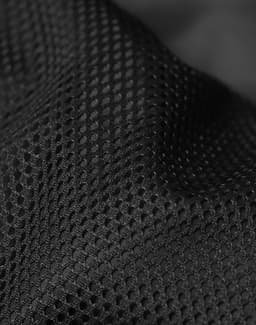 A close-up of black mesh fabric with a textured pattern, showcasing its breathable design and material quality.