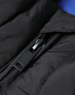 A close-up of a black insulated puffer vest showcasing the zipper and stitching details.