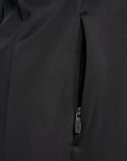 A close-up of a black softshell jacket featuring a zipped pocket. The fabric appears smooth and durable.