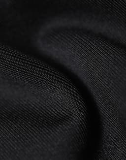 A close-up of a black softshell fabric, showcasing its smooth, textured surface. The material appears durable and flexible.