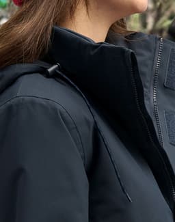 A unisex quilted waterproof jacket in navy blue, featuring a zip and adjustable hood, with a branding logo visible.