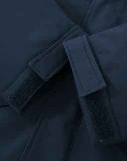 A close-up of a navy unisex quilted waterproof jacket featuring adjustable velcro cuffs and a smooth fabric finish.