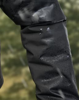 A close-up of a black waterproof jacket sleeve with droplets of water beading on the surface.