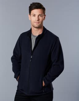 A man in a navy polar fleece jacket with a full zip, standing with hands in pockets against a grey background.