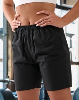 Unisex black mercerised cotton shorts with an elastic waistband, featured in a gym setting.