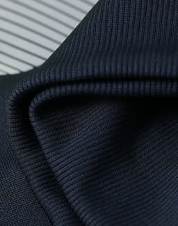 A close-up of textured, dark navy fabric with a ribbed pattern, showcasing its soft and flexible quality.