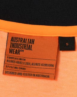 A close-up of an orange and black polo shirt with a label detailing standards and sizing. It has a logo.