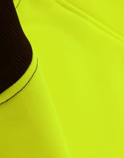 A close-up of a bright yellow fleece fabric with dark brown accents, featuring a logo.