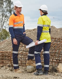Two workers in high-visibility workwear, wearing orange and yellow shirts with navy pants, on a construction site.