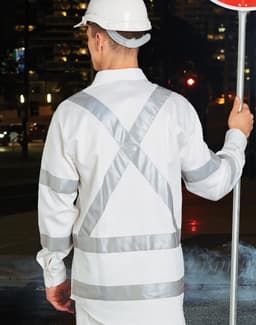 A safety shirt in white with reflective silver stripes, worn by a person holding a stop sign.