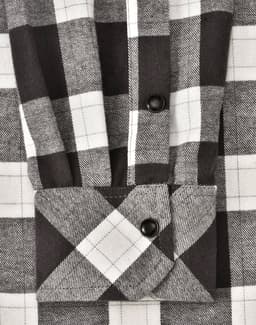 A black and white checkered flannel button-up shirt with a folded cuff, featuring a logo.