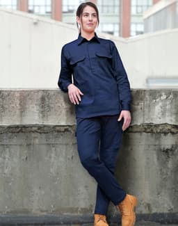 A navy long-sleeve work shirt with a closed front and two chest pockets, worn by a model. The model is leaning against a wall.