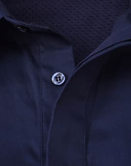 A navy blue long sleeve work shirt with a closed front and mesh interior. It features a button at the collar and has a branded logo.