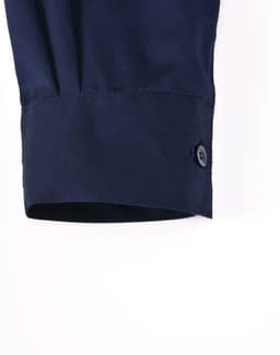 A navy long-sleeve work shirt featuring a closed front and buttoned cuff detail. It has a logo.