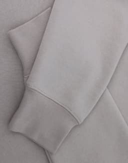 A light grey crewneck sweatshirt with a soft texture, featuring long sleeves and a cuffed hem.