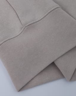 A light beige crew fleece jumper with a smooth texture and cuffed sleeves. It features a logo on the fabric.