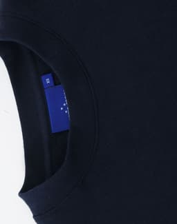 A navy crewneck sweatshirt with a ribbed collar and a logo tag visible on the inside seam.