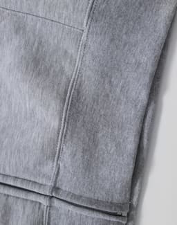 A grey men's full-zip fleecy hoodie with visible stitching details and a smooth fabric texture. Features a logo.