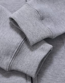 A grey full-zip fleecy hoodie featuring ribbed cuffs, highlighting texture and fabric detail. It has a logo.