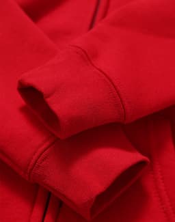 A red full-zip fleecy hoodie featuring cuffed sleeves and a soft texture, with an additional logo present.