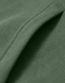 A close-up of a green fleece hoodie showcasing its soft fabric and stitching details. The hoodie has a logo.