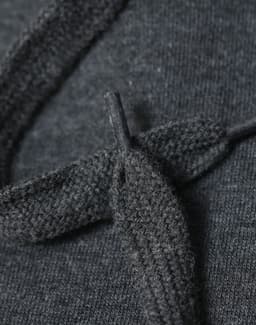 A close-up of a dark grey fleece hoodie showing the texture of the fabric and a knitted drawstring.