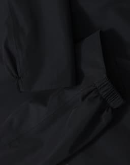 A waterproof jacket in black featuring elasticated cuffs and a durable fabric. The jacket has a logo present.