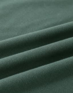 A close-up of a folded green cotton fabric, showcasing its soft texture and stretchability.