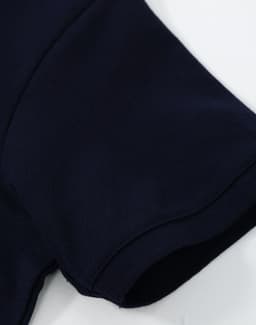 A navy blue ladies cotton stretch polo with a close-up view of the sleeve. It features a logo.