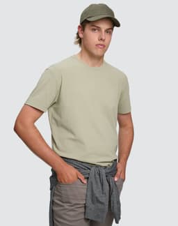 A light green men's premium cotton short sleeve tee shirt displayed on a model with a cap and grey shorts.