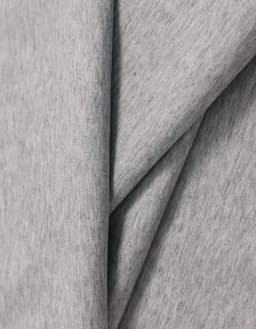 A close-up of light grey cotton fabric, showcasing its soft texture and smooth finish. The fabric has a logo.